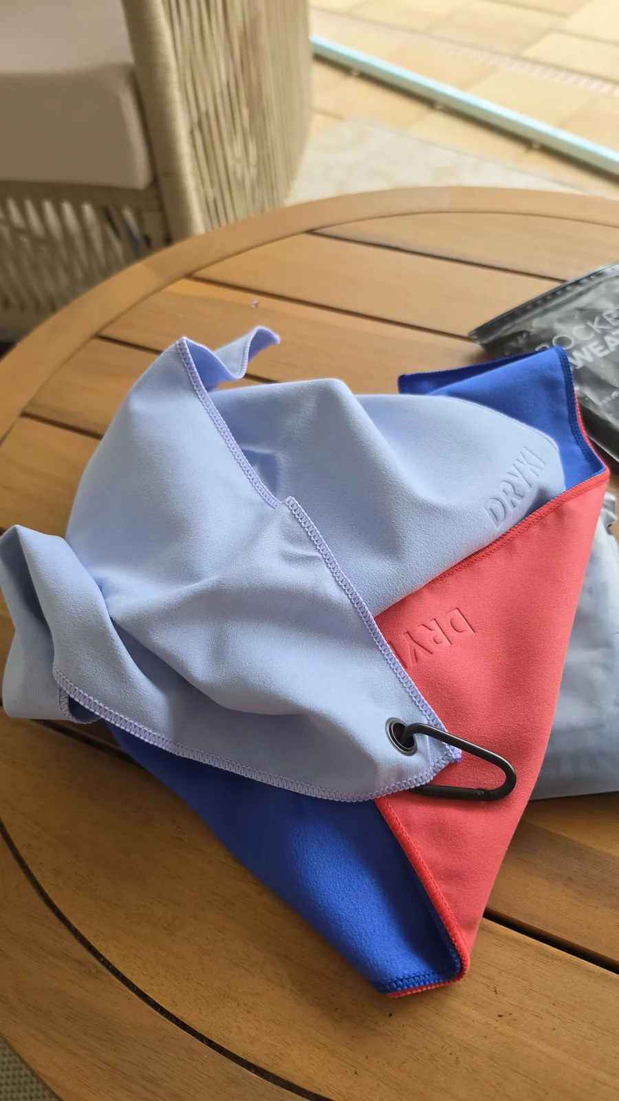 Loose blue, gray, and coral microfiber towels laid out on a wooden table.